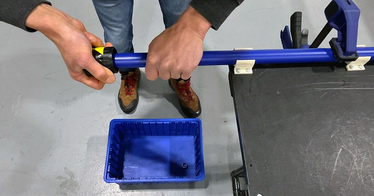 Hands using a deburring tool to clean the inner and outer edges of a Flexpipe tube after cutting.