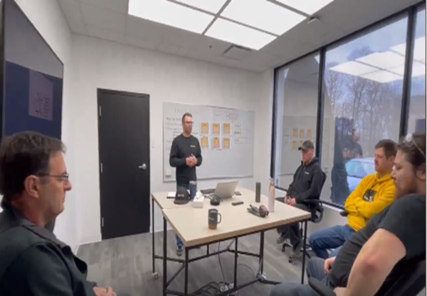 five people within a conference room discussing an upcoming warehouse optimization Kaizen event.