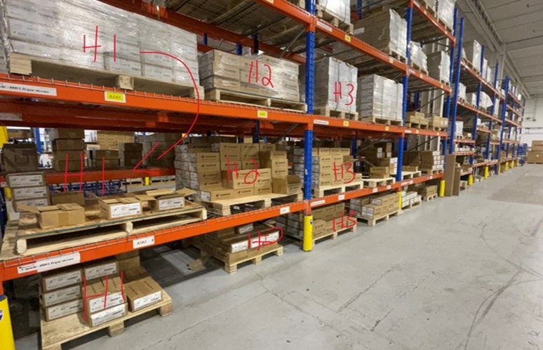 warehouse with fixed shelving four levels high with parcels on pallets within each level.
