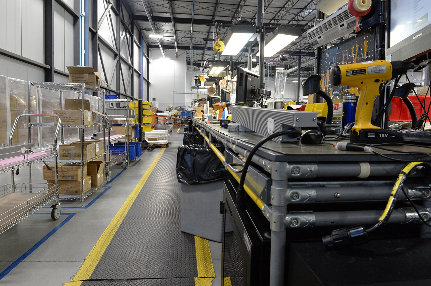 Assembly line with integrated storage, mobile wire rack carts, and workstation for electrical equipment production.
