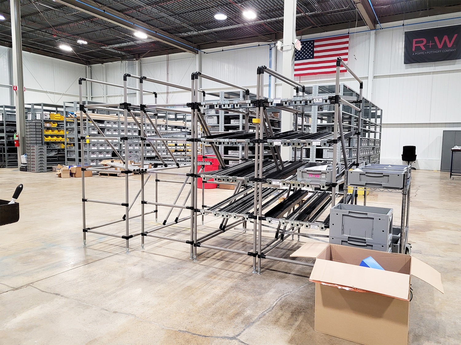 Modular flow rack system with roller tracks and storage shelves in an electrical equipment warehouse