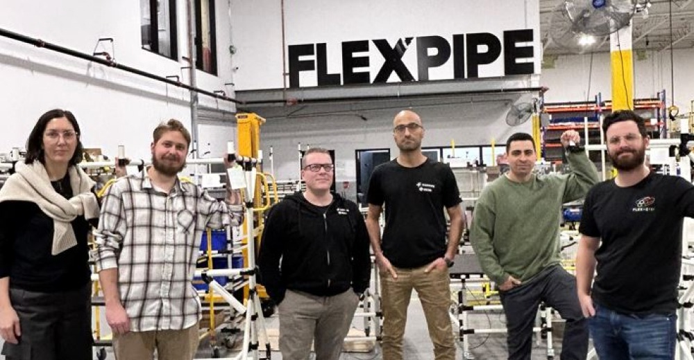 The Flexlab team at Flexpipe, standing in front of a modular structure assembly area, specializing in industrial design and material handling solutions.