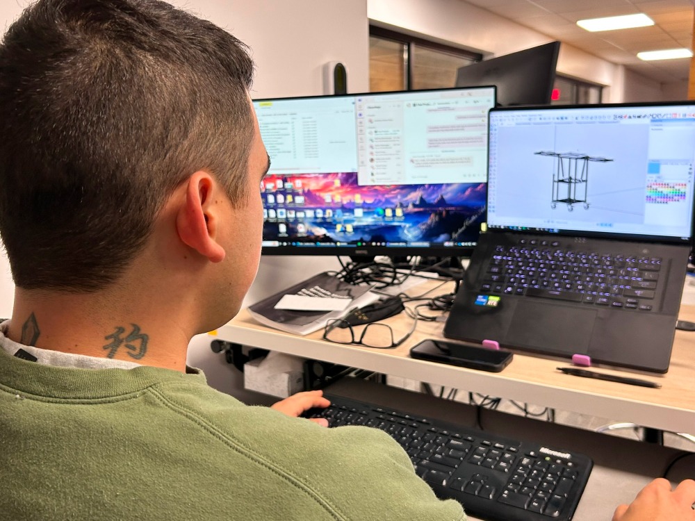 A Flexlab team member at Flexpipe working on a custom material handling structure using the Flexpipe Creator design tool on a laptop.
