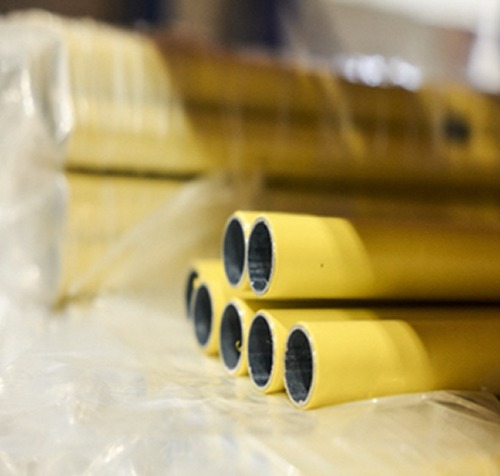 Close-up view of Flexpipe’s yellow polyethylene-coated galvanized steel pipes, stacked and wrapped for warehouse inventory or shipment.