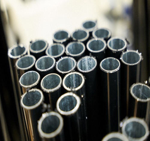 Bundle of black tubes – close-up of raw-cut ends. Close-up of a bundle of black polyethylene-coated tubes used in Flexpipe modular structures. The photo highlights the galvanized steel interior, visible from the raw-cut ends.