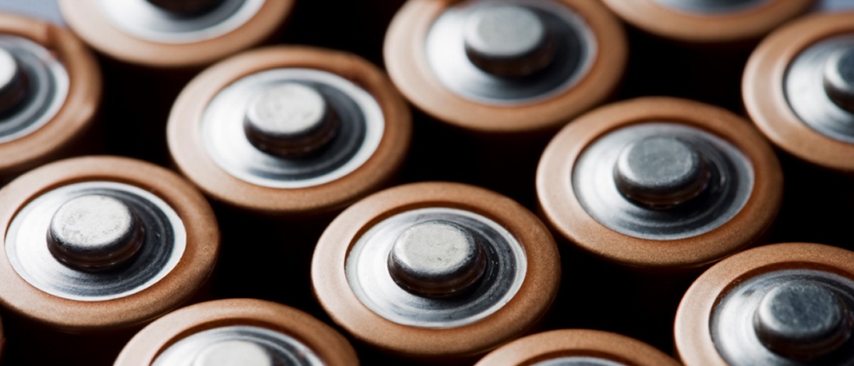 Close-up view of multiple AA batteries arranged in rows, showcasing the metallic tops of cylindrical energy cells used for power storage.