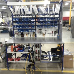 Organized industrial workstation with tool storage, flow racks, and shelving for efficient assembly operations