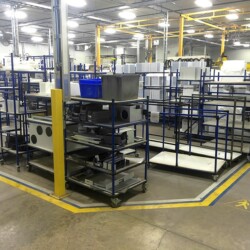 Plant view featuring modular material handling systems with storage carts, flow racks, and shelving for organized manufacturing operations